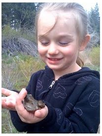girl in a field holding a frog 